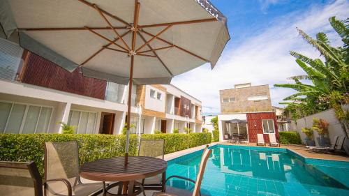 a table with an umbrella next to a swimming pool at Residencial Las Salinas in Maresias
