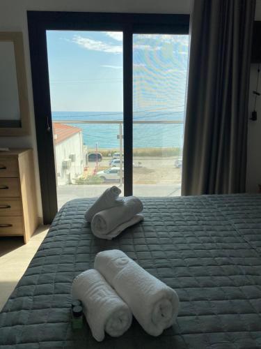 a bedroom with towels on a bed with a view of the ocean at Villa Loukas in Loutsa