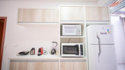 a kitchen with a white refrigerator and a microwave at Residencial Las Salinas in Maresias