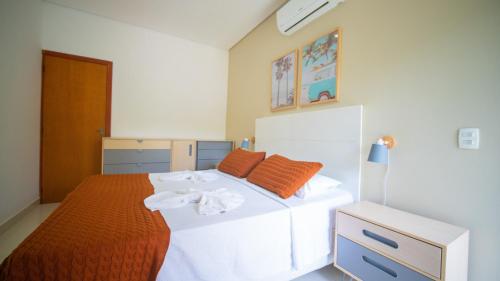 1 dormitorio con 1 cama blanca grande con sábanas de color naranja en Residencial Las Salinas en Maresias