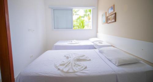 a bedroom with two beds with white sheets and a window at Residencial Las Salinas in Maresias