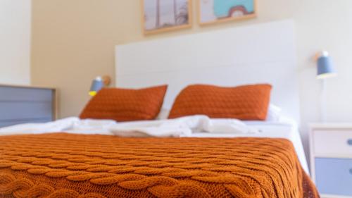 a bed with an orange blanket and orange pillows at Residencial Las Salinas in Maresias