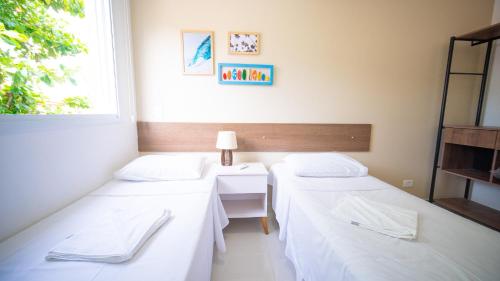two beds in a room with a window at Residencial Las Salinas in Maresias