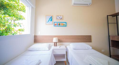 two beds in a room with a window at Residencial Las Salinas in Maresias