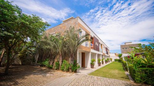 a brick building with palm trees in front of it at Residencial Las Salinas in Maresias