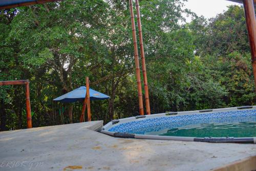 una piscina al aire libre con sombrilla y sombrilla en Hostal Caño Nevera, en La Macarena