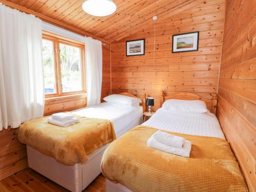a bedroom with two beds in a wooden cabin at Snowdon Vista Cabin in Caernarfon