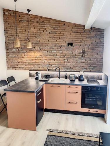 uma cozinha com um lavatório e uma parede de tijolos em Le Pantaléon - Sublime Studio Capitole em Toulouse