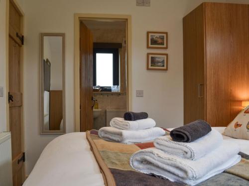 una pila de toallas sentadas encima de una cama en Osprey Lodge, en Westward