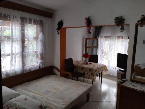a room with a table and two beds and windows at Akis Apartments in Mariaí