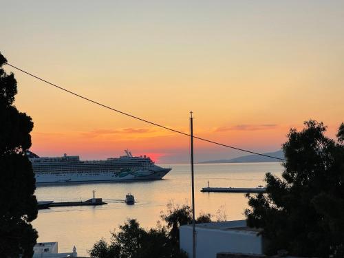 a cruise ship in the ocean at sunset at Rania Apartments Sea View in Mýkonos City