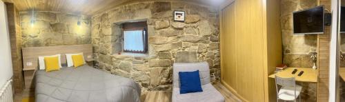 a bedroom with a stone wall with a bed in it at Casinhas da Capela in Tourém