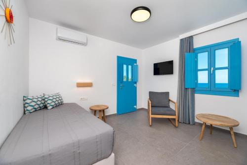 a bedroom with a bed and a blue door and a chair at Sigalas Beach Hotel in Kamari