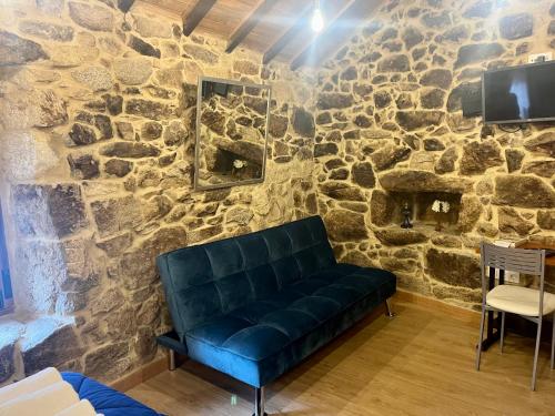 a couch in a room with a stone wall at Casinhas da Capela in Tourém