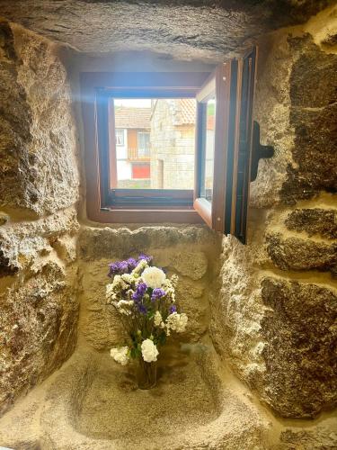 a vase of flowers sitting in front of a window at Casinhas da Capela in Tourém