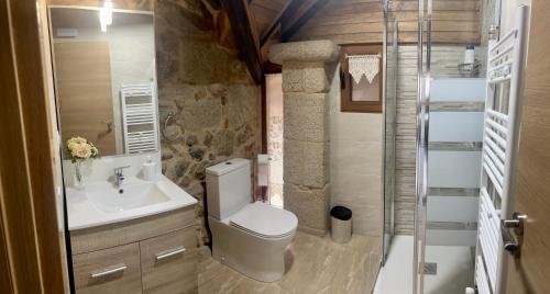 ein Bad mit einem WC, einem Waschbecken und einer Dusche in der Unterkunft Casinhas da Capela in Tourém