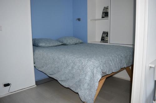 a small bedroom with a bed in a blue room at Studio avec loggia - à 200m de la plage - Parking in Courseulles-sur-Mer