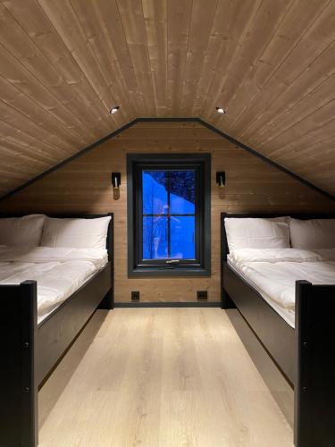 Stryn Mountain Lodge في سترين: سريرين في غرفة صغيرة مع نافذة