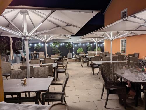 a restaurant with tables and chairs and white umbrellas at Hotel-Cafe Rathaus in Bad Abbach