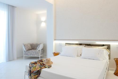 um quarto com uma grande cama branca e uma cadeira em OLIVETO A MARE - Suite & Apartment em Ascea