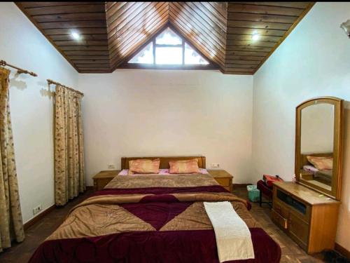 a bedroom with a bed and a window and a mirror at Woods Luxury Homestay in Nainital