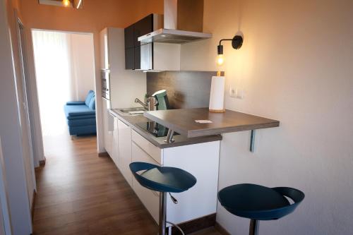a kitchen with two blue stools at a counter at Wohlfühloase am Trausdorfberg mit Sauna, Whirlpool und Panorama in Sankt Marein bei Graz