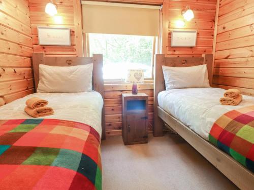 two beds in a room with wooden walls at Gisburn Forest Lodge in Skipton