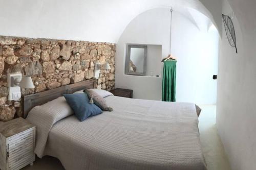 a bedroom with a large bed and a stone wall at Casa San Valentino in Vico del Gargano