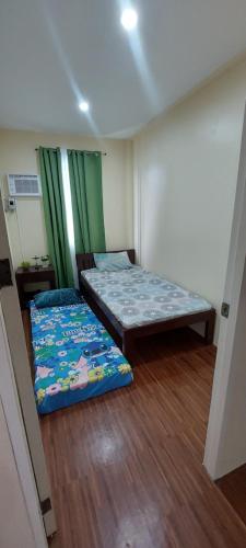 two beds in a room with green curtains at Affordable Home stay with 3 bedroom near CCLEX in Dapitan