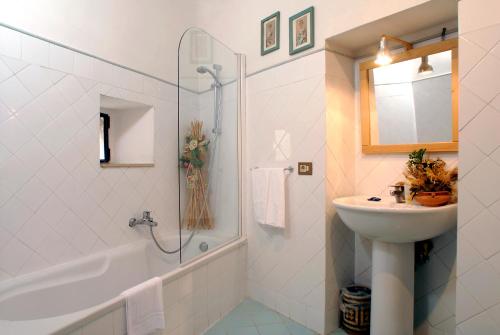 een witte badkamer met een wastafel, een bad en een wastafel bij Fattoria Guicciardini in San Gimignano