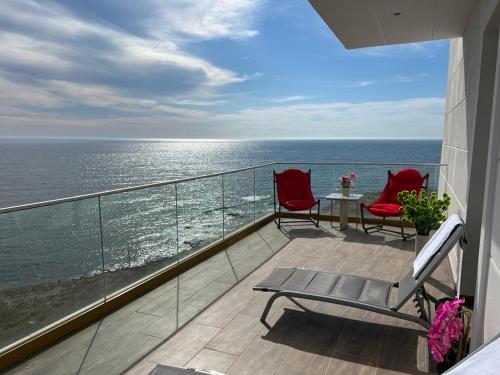 - un balcon avec deux chaises et une table donnant sur l'océan dans l'établissement Alessio Hotel Residence, à Costinesti