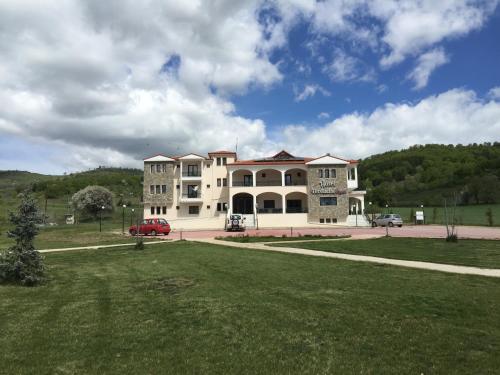 a large white building with a green field in front of it at Hotel Terelidis House in Varikón