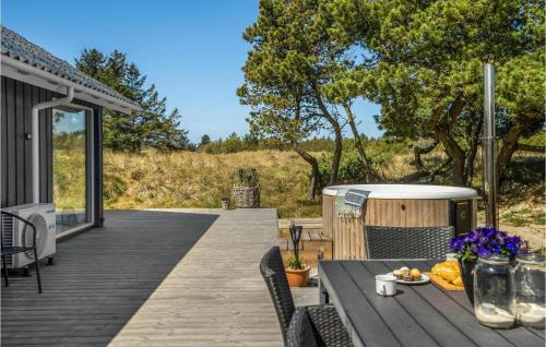 a wooden deck with a table and a hot tub at Holiday Home Tane Hedevej Blåvand X in Blåvand