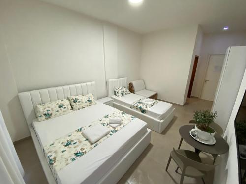 a small white bedroom with two beds and a table at Villa Arli&Eris in Vlorë