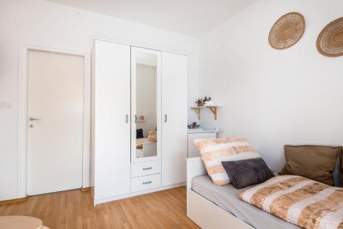 a white room with a couch and a mirror at Apartment and Rooms Dalmatiko in Vodice