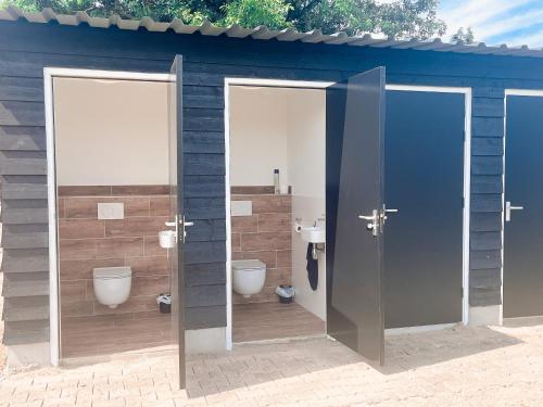 een badkamer met 2 toiletten en 2 kraampjes bij camping?glamping morskersweitje in Winterswijk