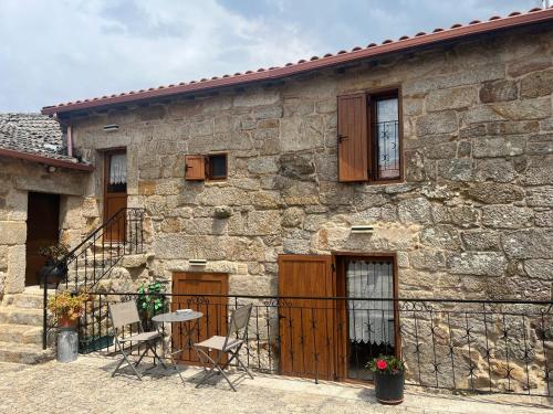 a stone house with chairs and a table in front of it at Casinhas da Capela in Tourém