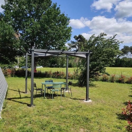a picnic table and chairs under a canopy in a field at Tipi Apache des monteaux in Vivy