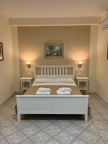 a bedroom with a white bed with two tables at Casa Tacconi in Villasimius