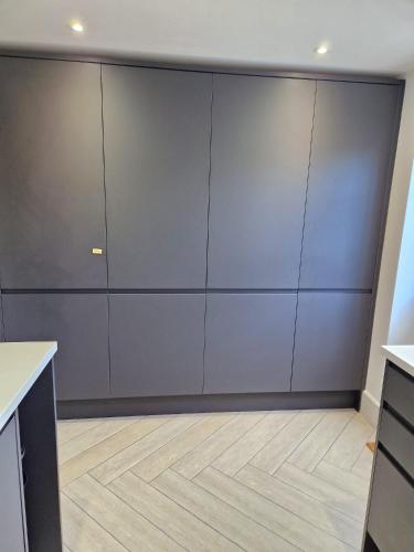 a kitchen with gray cabinets and a wooden floor at Wesley Chapel- Cyanacottages in Whitby