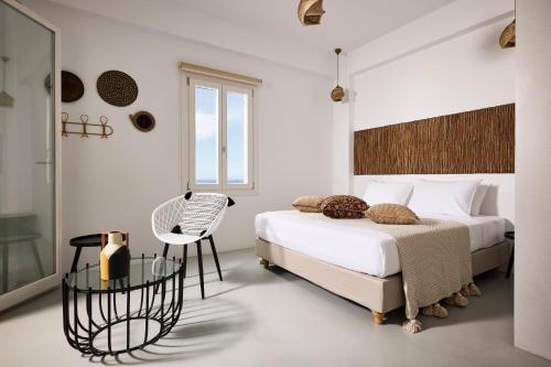 um quarto branco com 2 camas e uma mesa de vidro em Ianemi Suites by K4 Kythnos em Kythnos