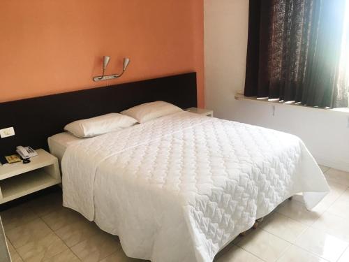 a bedroom with a white bed and a window at HOTEL ITACAIUNAS in Marabá