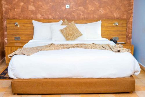 a bedroom with a large white bed with a wooden headboard at Midindi Hotel in Accra