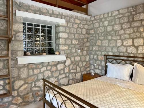 Casa Matina, GcollectionGr في Didyma: غرفة نوم بحائط حجري مع سرير ونافذة