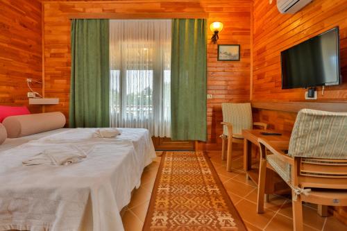 a room with a bed and a table and a television at Çıralı Orange Motel in Cıralı