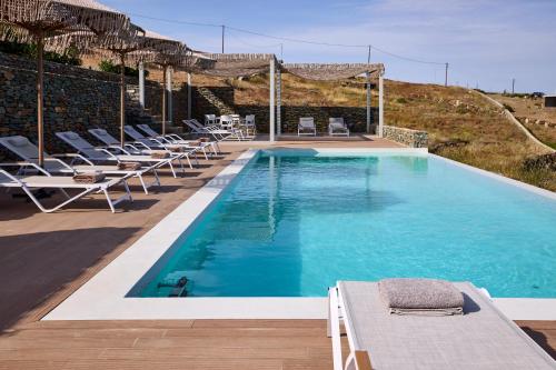 a large swimming pool with lounge chairs at Ianemi Suites by K4 Kythnos in Kithnos