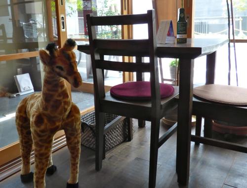 a giraffe toy sitting on a chair next to a table at Guesthouse Hyakumanben Cross in Kyoto