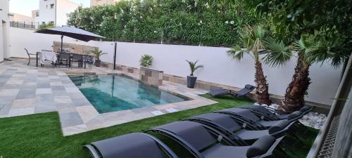 une cour avec une piscine bordée de chaises et d'arbres dans l'établissement la maison d'amiata avec piscine, à Agde
