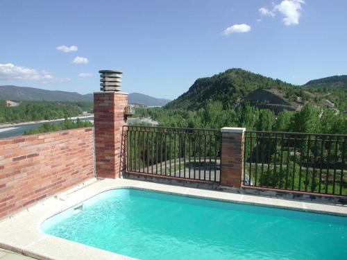 a swimming pool with a fence and mountains in the background at Hotel Dos Rios Central in Aínsa