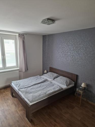 1 dormitorio con 1 cama con pared gris en Apartmán Eliášova en Česká Lípa